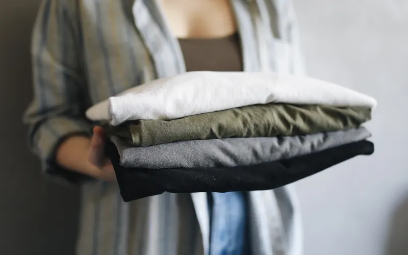 Hands holding a stack of neatly folded shirts