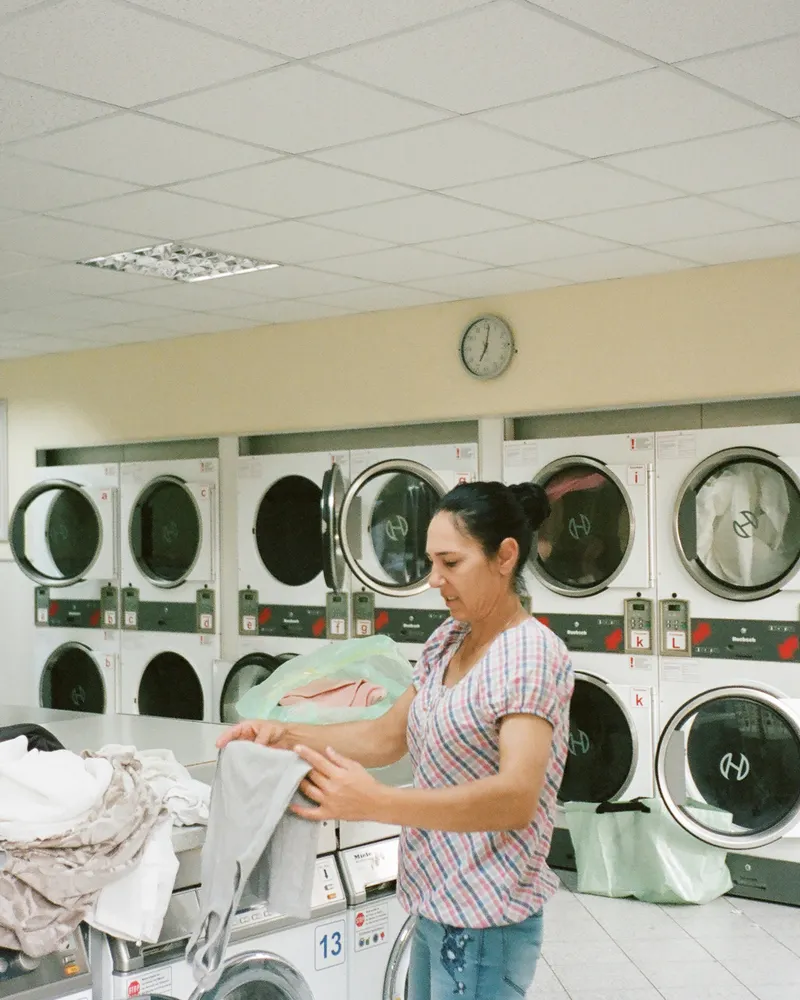 Woman sorting laundry beside a row of front-load washing machines