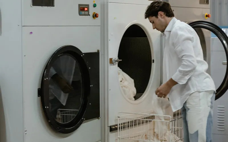 Man loading clothes into a large washing machine