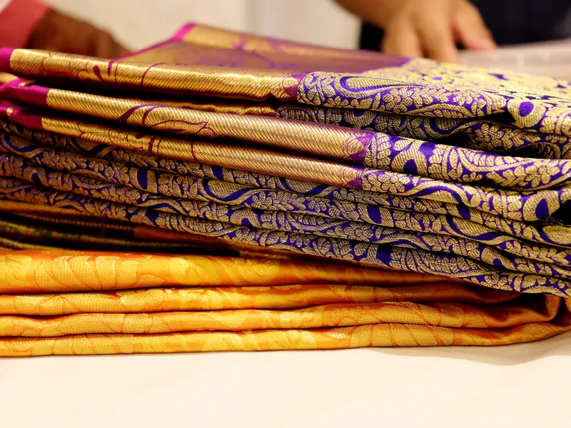Stack of folded silk sarees with gold woven borders